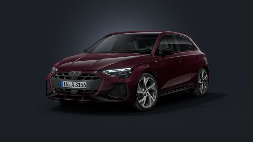 Der Audi A3 Sportback mit Individuallackierung Audi exclusive in Shirazrot Metallic schräg von vorne auf dunklem Hintergrund.
